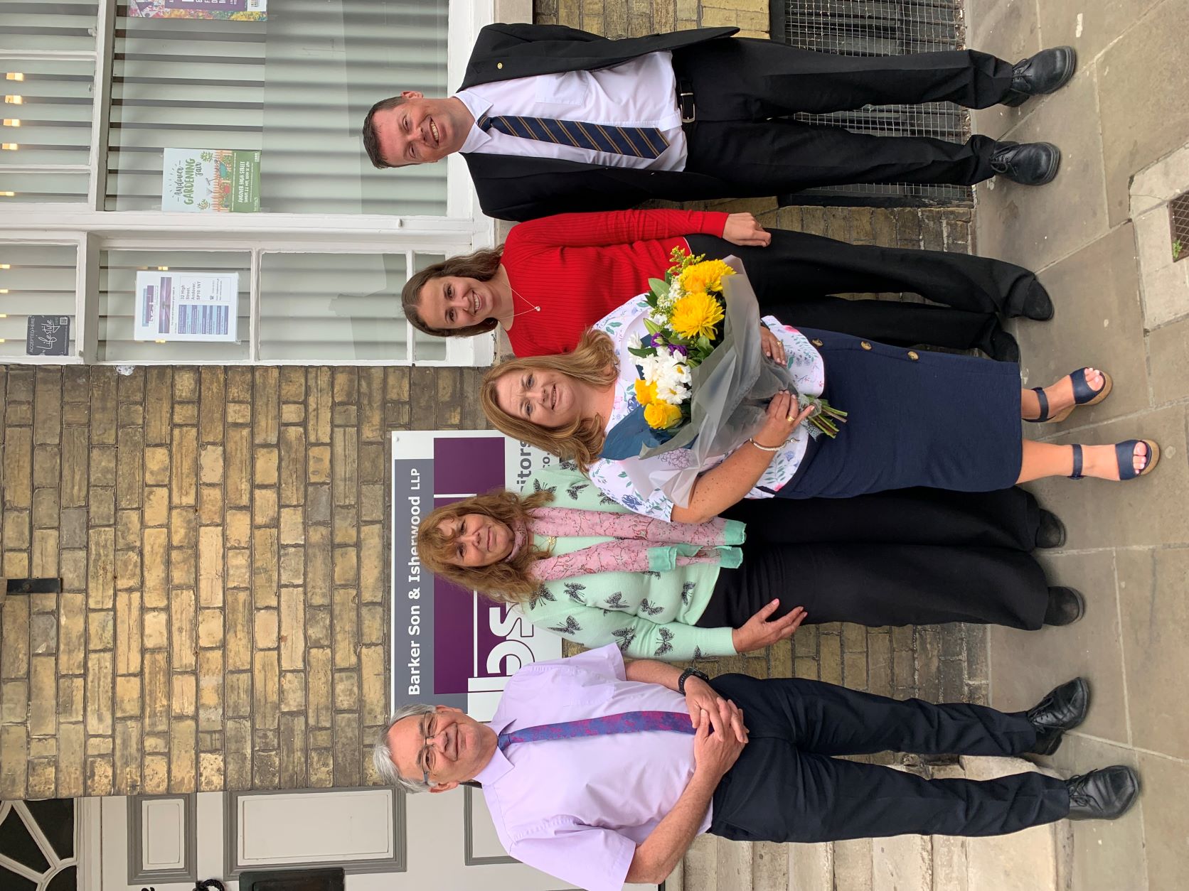 Litigation team stood out front of office celebrating thrity years of rachel barr.